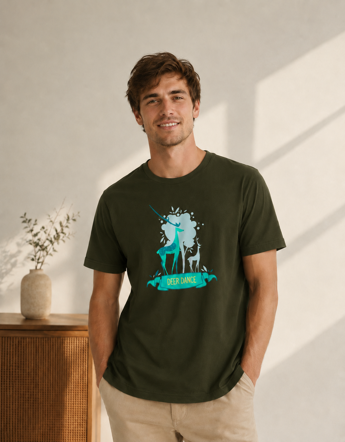 Man wearing a green t-shirt with a graphic design, standing in a room with a wooden cabinet and plant.