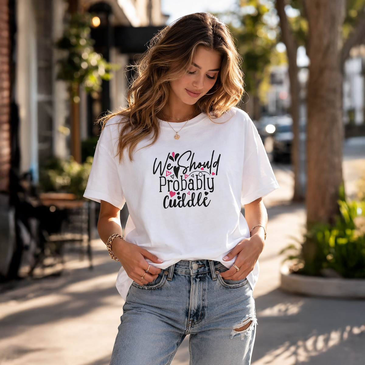 Woman wearing a white t-shirt with text and graphic, standing outdoors.
