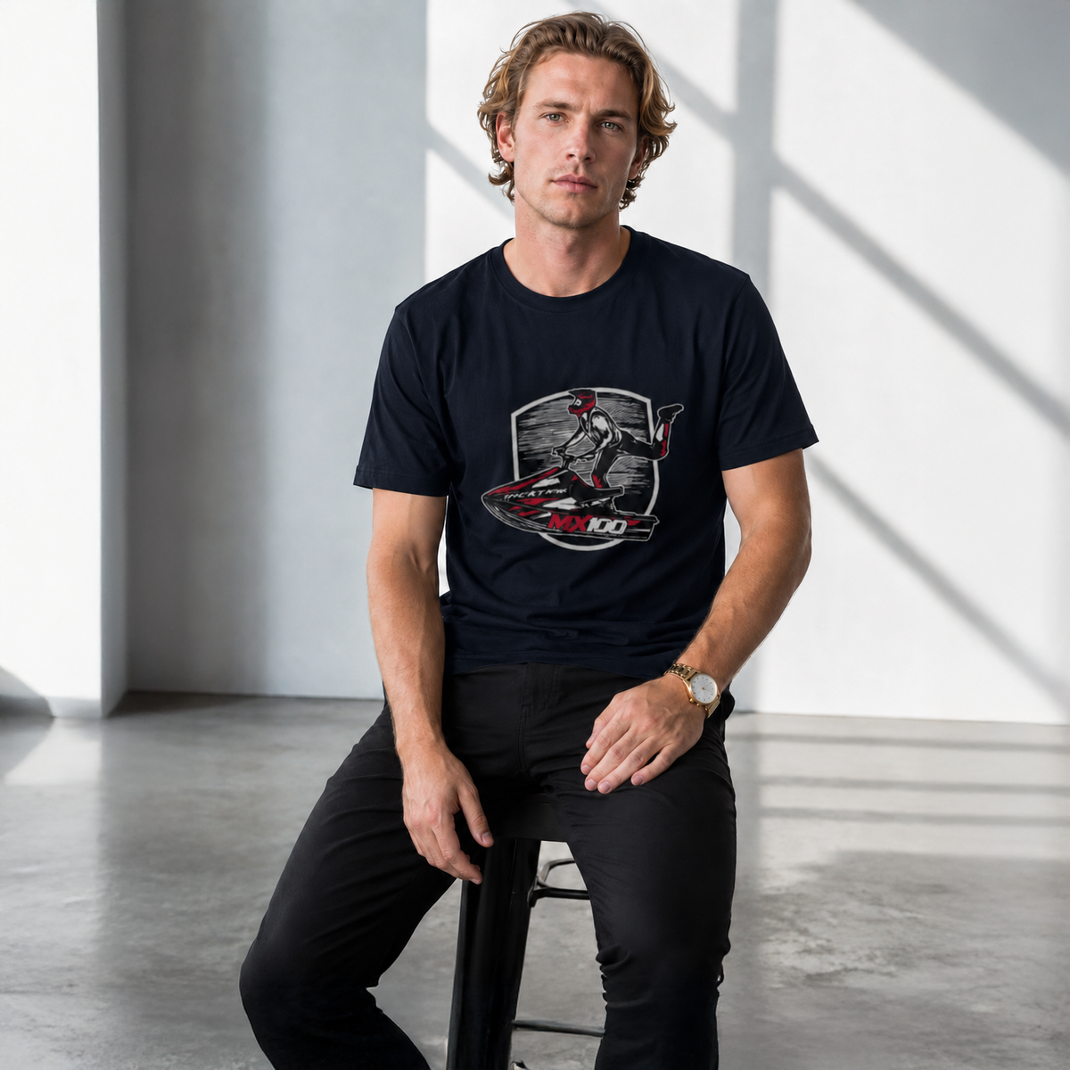 Man wearing a black t-shirt with a graphic design sitting on a stool.