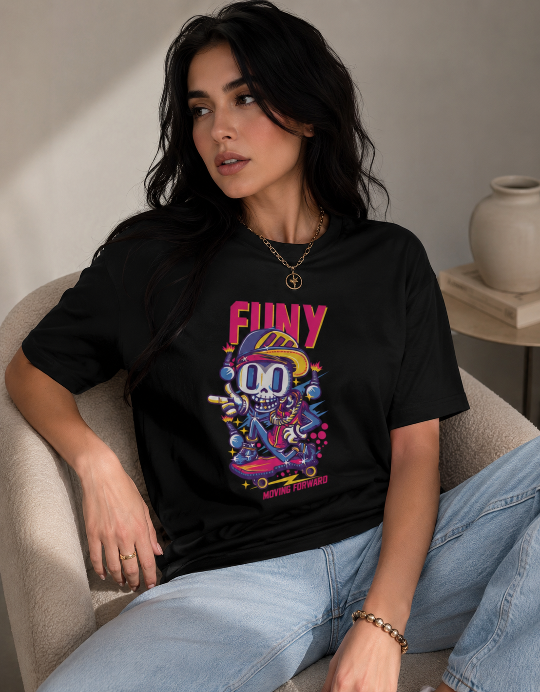 Woman wearing a black t-shirt with colorful graphic design sitting on a beige chair.