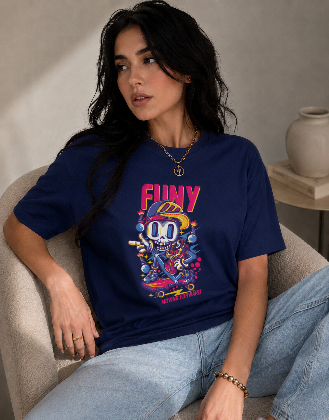 Woman wearing a navy blue t-shirt with colorful graphics and text, sitting on a beige armchair.