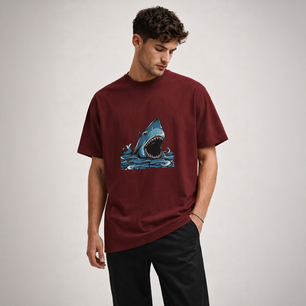 Man wearing a maroon t-shirt with a shark graphic on a plain background