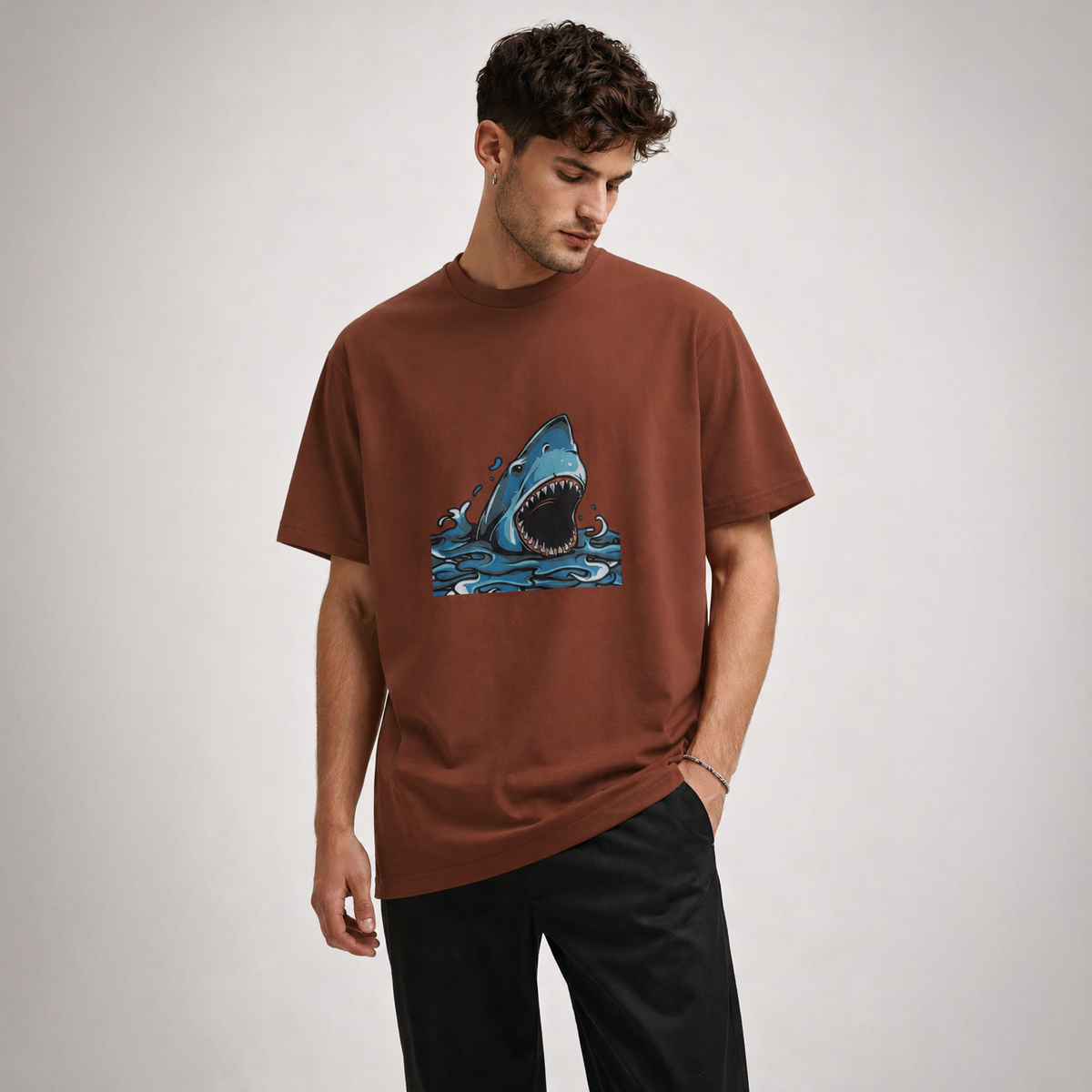 Man wearing a brown t-shirt with a shark graphic on a plain background