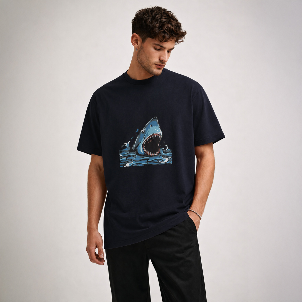 Man wearing a black t-shirt with a shark graphic on a plain background