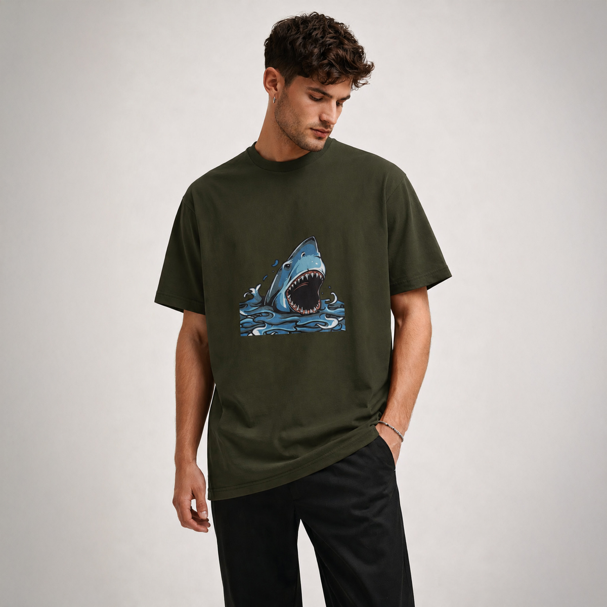 Man wearing a green t-shirt with a shark graphic on a plain background