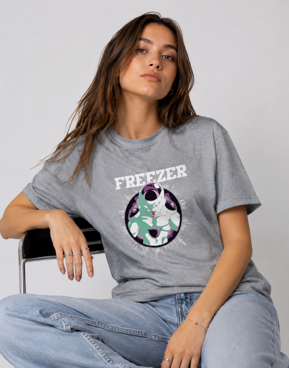 Woman wearing a gray t-shirt with a graphic design and text, sitting on a chair against a plain background.